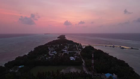 Magische-Drohnenaufnahme-Nach-Sonnenuntergang-Auf-Den-Malediven,-Die-über-Eine-Insel-Mit-Wolken-In-Der-Ferne-Und-Rosafarbenem-Himmel-Fliegt