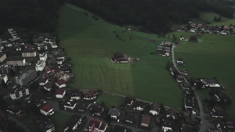 Drone-aerial-over-switzerland-town-of-Endelberg-pan-up-to-reveal-huge-mountain-ranges-on-a-cloudy-day
