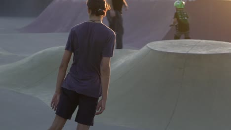 Slow-motion-shot-of-boy-on-skateboard-riding-at-park-during-sunset
