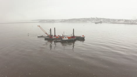 Circling-a-barge-in-the-Atlantic-Ocean-on-a-cold,-snowy,-winter-day