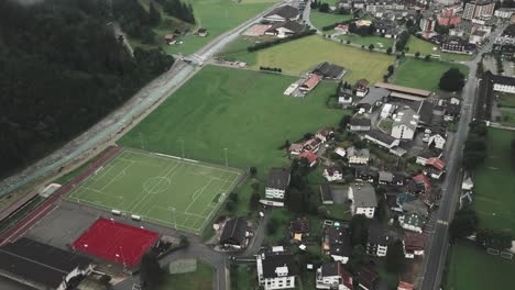 Drone-aerial-over-soccer,-tennis,-futbal-and-basketball-court-in-a-small-town-of-Endelberg-surrounded-by-grass-lands