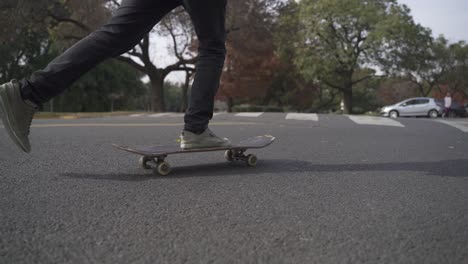 Close-up-of-skateboard-being-ride-on-the-street-with-park-at-background