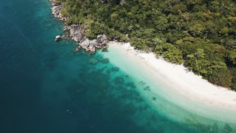 Drone-aerial-pan-down-to-show-tropical-blue-clear-water-and-rocks-on-Fitzroy-island-with-paddle-boards
