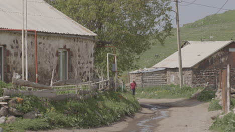 Man-Walking-On-Dirt-Path-With-Traditional-Houses-View-In-A-Small-Village-Of-Moliti-By-Tabatskuri-Lake-In-Georgia
