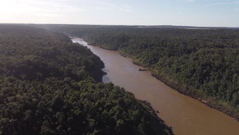 Aerial-view-of-flowing-dirty-Brown-colored-Iguazu-River-in-middle-of-Amazon-Rainforest-at-sunlight