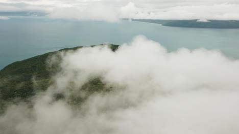 Drone-aerial-panning-around-tropical-forest-island-above-the-clouds