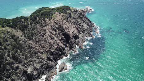 Drone-aerial-going-from-lighthouse-to-beautiful-blue-ocean-with-a-pan-down