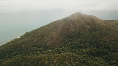 Drone-aerial-in-the-clouds-over-tropical-forest-Fitzroy-island-showing-blue-water-in-Queensland
