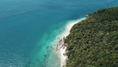 Drone-aerial-pans-around-to-show-a-tropical-island-with-clear-blue-water-and-sandy-beaches-on-Nudie-beach