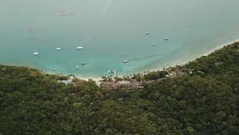 Panorámica-Aérea-De-Drones-Sobre-Fitzroy-Island-Resort-Y-Barcos-En-El-Agua-Azul-Transparente-Tropical