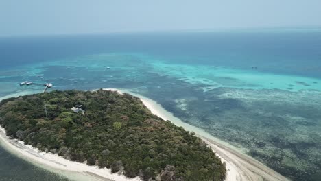 Antena-De-Drones-Sobre-Una-Pequeña-Isla-De-Bosque-Tropical-Alrededor-De-Un-Arrecife-Azul-Claro