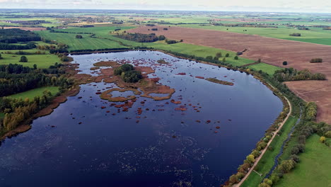 Aerial-View-of-Idyllic-Countryside-Lake-and-Plain-Agricultural-Fiends-Drone-Shot