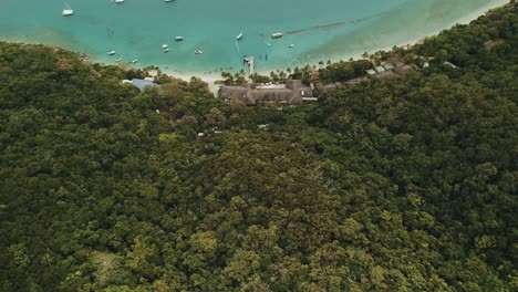 Drone-aerial-pan-up-over-Fitzroy-island-resort-and-boats-on-the-tropical-blue-clear-water-on-a-sunny-day