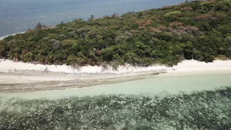 Antena-De-Drones-Sobre-Una-Pequeña-Isla-Tropical-Con-Agua-Azul-Clara-Y-Bote-Junto-Al-Arrecife