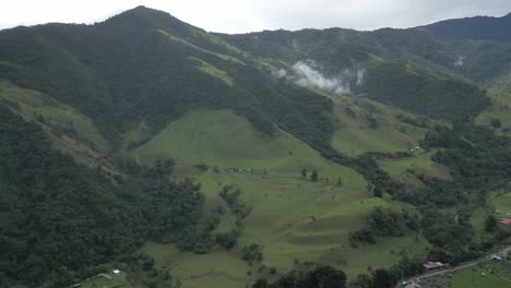 Drone-Aéreo-Panorámico-Justo-Encima-Del-Valle-De-Cocora-Picos-Montañosos-Nubes-Senderismo-Ciudad,-Región-Nacional-Protegida-No-Contaminada-En-Salento-Colombia
