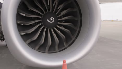 Airplane-engine-windmilling-while-parked-on-airport-tarmac,-close-up