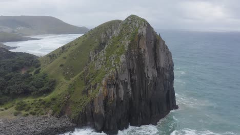 Drone-flying-towards-rocky-cliff-and-green-grass-rolling-hills-Transkei,-South-Africa
