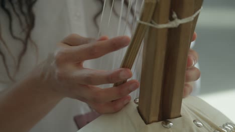 Female-hands-playing-Kora-strings-percussion-African-harp-in-a-warm-daylight-ambient,-close-up-shot