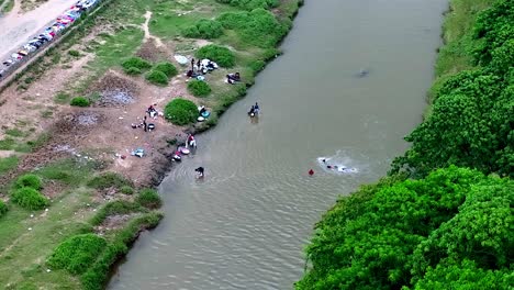 Aerial-top-down-of-Haitian-kids-swimming-in-dirty-river-and-adults-washing-clothes---poor-country-of-Haiti