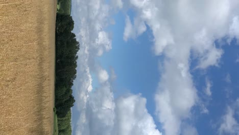 Lapso-De-Tiempo-Vertical-De-Las-Nubes-Que-Pasan-Rápido-Sobre-Un-Campo-De-Tierra-Agrícola-Cultivado-En-El-Campo