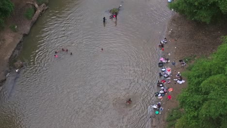 Authentic-real-life-scene-of-children-playing-on-Massacre-river-waters-while-women-wash-clothes