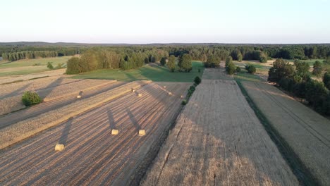 Blick-Auf-Den-Sonnenuntergang-Aus-Der-Luft-Auf-Die-Weizenplantage-Mit-Heuballen-Auf-Dem-Ackerland-Während-Der-Goldenen-Stunden