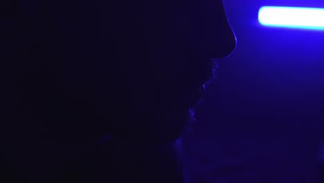 Rotierender-Silhouettenschuss-Von-Der-Seite-Des-Gesichts-Eines-Mannes-In-Blauem-Licht