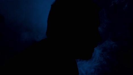 Silhouette-shot-of-a-man-inhaling-and-exhaling-smoke-from-a-vape