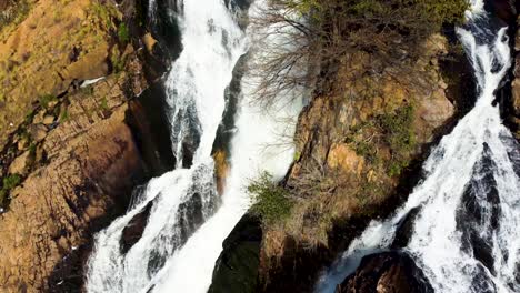 A-stream-of-water-flowing-down-African-rocks-creating-a-small-waterfall-in-Hartebeesport-Dam,-North-West,-South-Africa