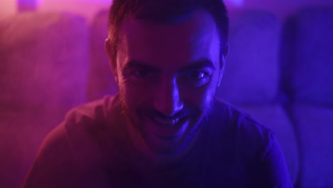 Close-up-shot-of-a-man-laughing-in-a-sinister-fashion-with-fog-and-vibrant-lights