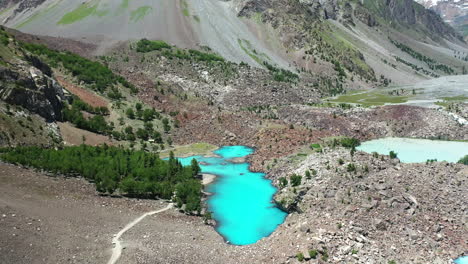 Cinematic-aerial-shot-of-turquoise-colored-water-in-the-mountains-at-Naltar-Valley-in-Pakistan,-slow-revealing-drone-shot