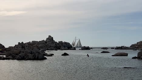 Zweimast-Segelschiff-überquert-Die-Szene-In-Cala-Della-Chiesa-Auf-Der-Insel-Lavezzi-In-Korsika-Mit-Menschen,-Die-Baden,-Frankreich