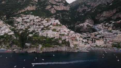 Boats-Sailing-Across-The-Waterfront-Village-Of-Positano-In-Amalfi-Coast,-Southern-Italy