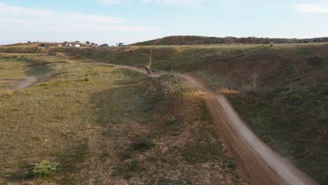 Dolly-Drohnenaufnahme-Einer-Staubigen-Motocross-Strecke-In-Malaga-In-Spanien,-Wo-An-Einem-Sonnigen-Tag-Ein-Rennen-Von-Motorradfahrern-Mit-Gefährlichen-Stunts-über-Hügel-Gefahren-Wird