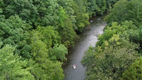 An-aerial-view-of-people-rafting-on-a-river-bordered-by-the-forest