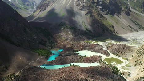 Cinematic-drone-shot-starting-on-turquoise-colored-water-then-revealing-the-mountains-at-Naltar-Valley-in-Pakistan,-aerial-shot