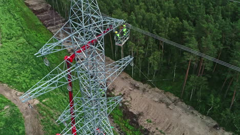 Workers-on-high-voltage-pylon-and-surrounding-landscape
