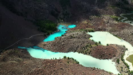 Drone-shot-of-turquoise-colored-water-in-the-mountains-at-Naltar-Valley-in-Pakistan,-slowly-descending-and-rotating-aerial-shot