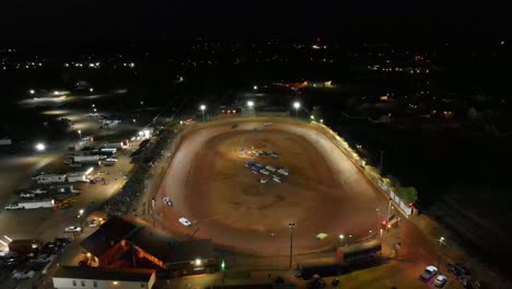 Aerial-flyover-of-oval-dirt-track-racing-during-a-race-at-night