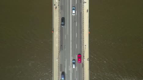 Zoom-in-of-bridge-road-over-a-river,-with-boat-sailing-underneath
