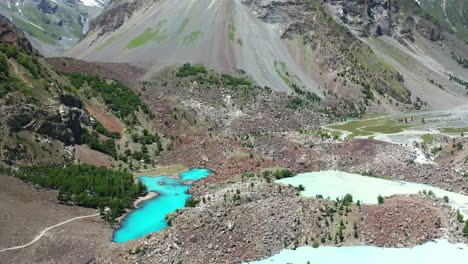Drone-shot-of-turquoise-colored-water-in-the-mountains-at-Naltar-Valley-in-Pakistan,-slowly-tilting-upward-aerial-shot