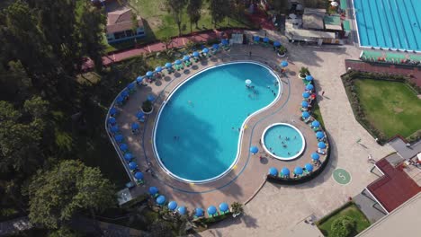 Drone-video-of-a-swimming-pool-surrounded-by-sun-shade-umbrellas