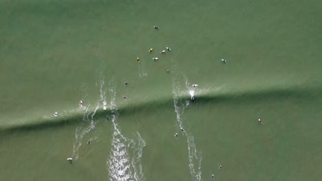 surfer-at-the-point-of-the-reef-break-les-grenettes-on-the-island-of-Ré-in-France,-from-above-with-the-drone,-wave-is-moving