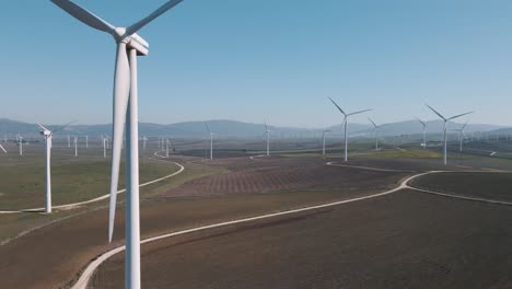 Rising-up-slow-turning-renewable-energy-wind-turbine-on-wind-farm-landscape-aerial-view