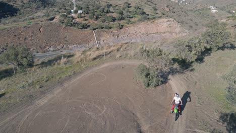 Statische-Luftaufnahme-Einer-Staubigen-Motocross-Strecke-In-Malaga,-Spanien,-An-Einer-Autobahn,-Während-Ein-Motocross-Fahrer-Eine-Kurve-Macht