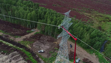 Top-rotating-shot-of-workers-installating-of-electric-power-pole-using-a-red-crane-at-daytime
