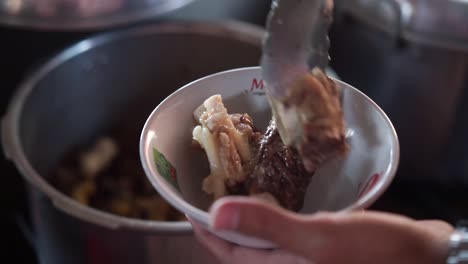 Hands-take-beef-bones-from-pot-to-bowl