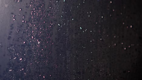 Kondenswassertropfen-In-Einem-Glasfenster-Aufgrund-Des-Regens-Beleuchteten-Bunte-Reflexionen-Auf-Den-Regentropfen