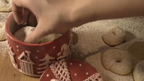 Woman-hands-putting-handmade-cookies-in-a-cookie-jar