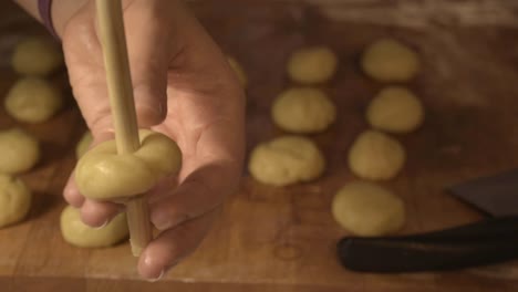 Making-holes-in-the-cookie-dough-to-model-them-as-doughnuts,-with-the-use-of-the-wooden-spoon